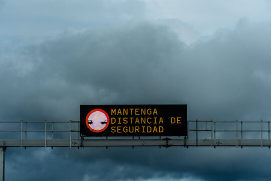 The road sign in Spanish reminds drivers to keep a safe distance on a cloudy day.
