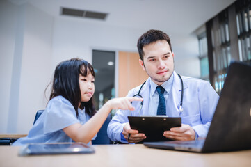 Fototapeta premium A girl is pointing at a male doctor's laptop to ask about health problems.
