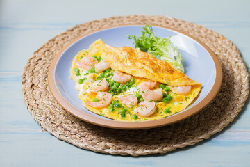Prawn omelette with green peas on blue plate. Eggs with shrimps