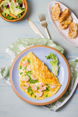 Prawn omelette with green peas on blue plate. Eggs with shrimps. High angle view