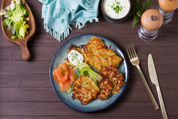 Potato hash browns with smoked salmon and cucumbers. Potato cakes or vegetable fritters, patties. View from above, top view