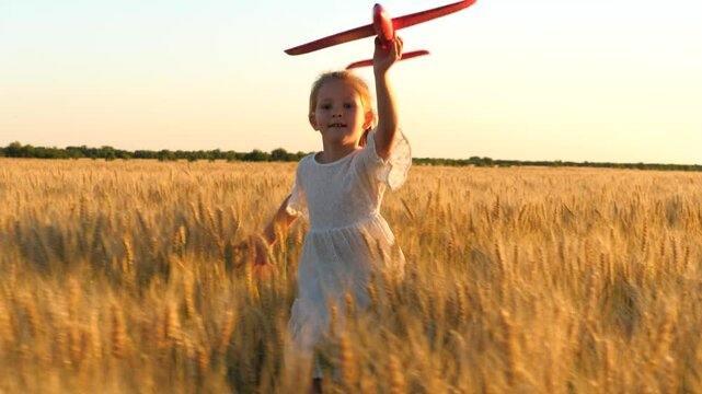 little child girl kid daughter runs through wheat field with toy plane her hand sunset, happy family dream fly, child runs park across field, child dreams becoming pilot, kid plays with toy plane