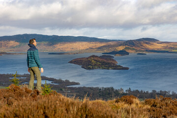 Fototapeta premium Male hiker, outdoor person enjoying view Scottish Highlands and Loch Lomond