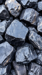 Dark grey rocks piled outdoors, sunlight reflecting