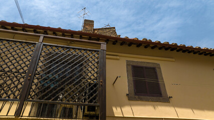 Window and balcony of a house in a village. The wall is yellow. In the background the blue sky.