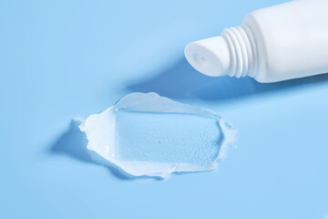 White lip balm in a tube on a blue background. The texture.