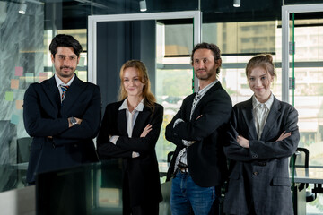 Team of confident businessmen and businesswomen standing together in office. Crossed arms and...