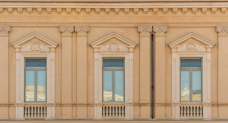 Three Italian windows on the old wall facade with one open and two closed wooden shabby brown...
