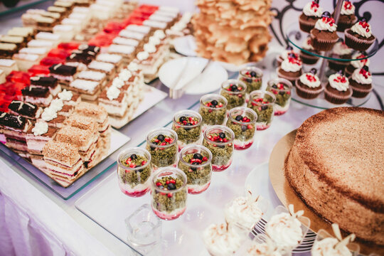 Mini desserts in glass jars served at a catering event. Gourmet sweet treats for banquets, corporate parties and buffet tables. Elegant and delicious pastry selection for special occasions.