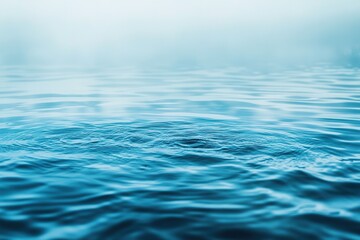 Naklejka premium Calm blue water ripples under a misty sky creating a serene peaceful scene