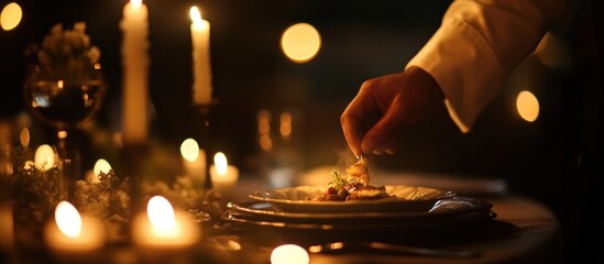 A chef adds the final touch to a meal by candlelight creating an intimate and warm ambiance