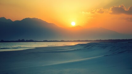 Fototapeta premium Distant mountains silhouetted against a sunset over a pristine white beach