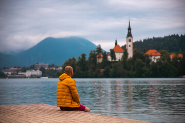 Man sitting on wooden deck, pier at Bled lake, Slovenia