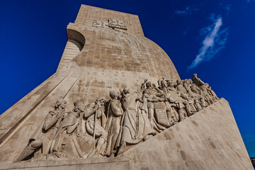 Exploring the intricate carvings of the Monument of the Discoveries in Lisbon, Portugal against a stunning blue sky
