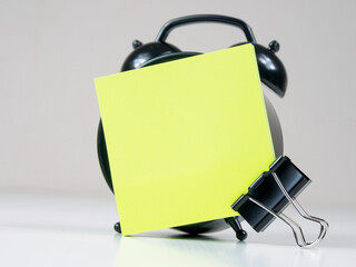 A blank reminder sticker and alarm clock inspire productivity, creating space for ideas and plans.