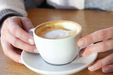 Female hand holding a cup of cappuccino