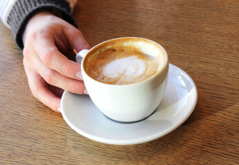 Female hand holding a cup of cappuccino