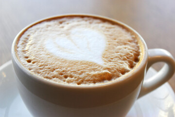 Cup of cappuccino on wooden table in cafe