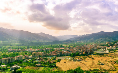 beautiful evening or morning landscape of amazing small mountain town in highland walley with houses and orange roofs and nice sunset cloudy sky with mountains on background