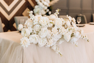 Reception table decorated with roses. Bride and groom presidium