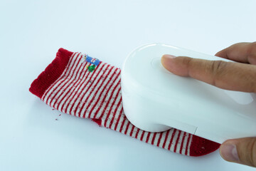 Female hand holding pellet cleaner, cleaning baby sock. Garment care concept.