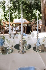 silver candlesticks, flowers and vases on a table decorated in a restaurant on the terrace outdoors