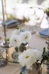 silver candlesticks, flowers and vases on a table decorated in a restaurant on the terrace outdoors
