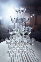Pyramid of wine glasses on a table in a restaurant under lights. Luxury catering for a celebration