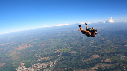  A Brazilian skydiver in free fall, on a summer day. Smiling and confident.