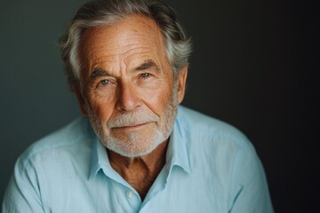 Obraz premium Close-up portrait of a pensive, elderly man with gray hair and beard, wearing a light blue shirt.