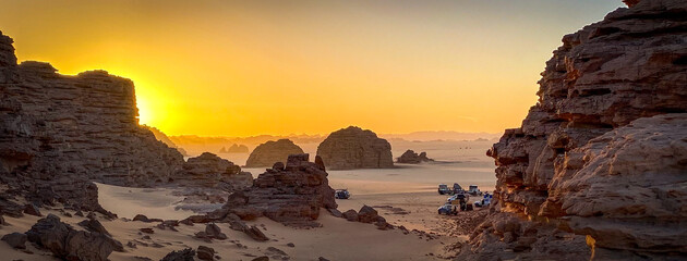 A group of 4x4 campers set up camp among the rock formations that jut out of the sand of Tadrart...