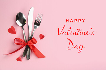 Happy Valentine's day card. Cutlery tied with red ribbon and paper hearts on pink background, top view