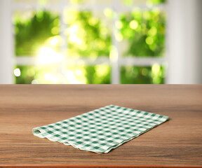 Green checkered tablecloth on wooden table in room, closeup