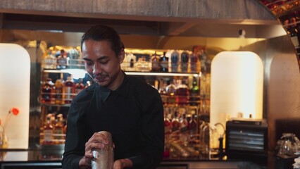 Asian smart bartender shaking mixed cocktail preparing to serve at luxurious counter preparation, making special drink looking at camera fronted view. Special refresh drink nightlife luxury. Vinosity.