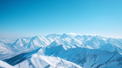 Endless snowy mountain ridges stretch under a bright blue sky, evoking a sense of vast wilderness and freedom.