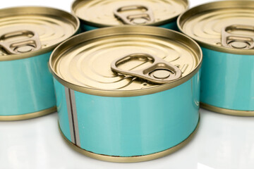 Four metal cans of tuna, close-up, isolated on a white background.