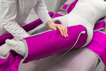A therapist fastening a pressotherapy leg sleeve on a patient, preparing for a professional lymphatic drainage session.