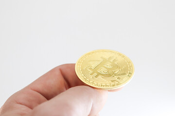 Close-up of a hand making the gesture of throwing a bitcoin on a white background. Heads or tails...