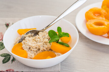 Fragrant oatmeal with tender peaches in a white bowl
