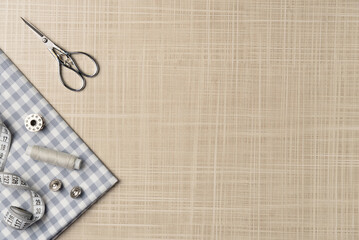 Sewing accessories on the table. Fabric, thread, buttons, scissors, bobbin. Flat lay, top view. Copy space
