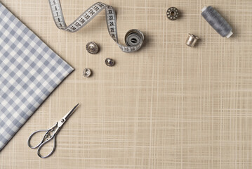 Sewing accessories on the table. Fabric, thread, buttons, scissors, thimble, bobbin. Flat lay, top...