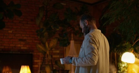 A man talks on a mobile phone and uses a laptop during night work from home