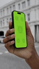 N SCREEN CHROMA KEY Person holding a smartphone with a green screen on a city street, showcasing...