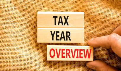 Tax year overview symbol. Concept words Tax year overview on beautiful wooden blocks. Beautiful canvas background. Businessman hand. Business tax year overview concept. Copy space.