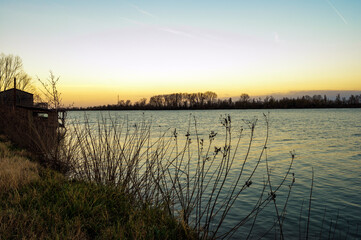 Obraz premium winter sunset over the Scardovari lagoon with fishing boats and cabins inside the delta of the river Po, Porto Tolle, Veneto