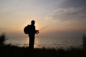 Silhouette of a man fishing at sunset