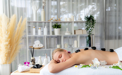 Hot stone massage at spa salon in luxury resort with day light serenity ambient, blissful woman...