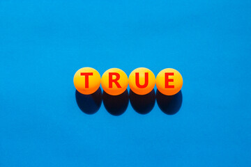 True symbol. Concept word True on beautiful yellow ping pong balls. Beautiful blue table blue...