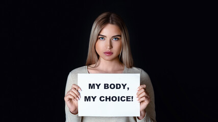 Human rights freedom. Sad woman holds inscription my body my choice, isolated on black background,...