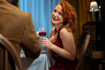 Elegant woman laughing during romantic dinner with red wine